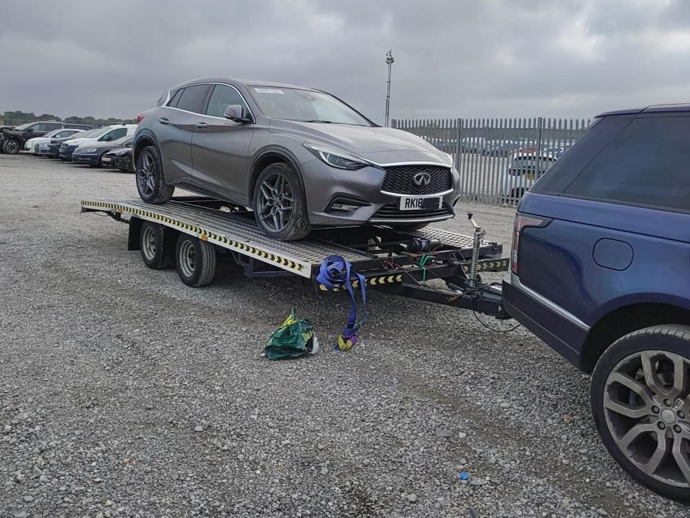 Infiniti Q30 loaded on a trailer at a vehicle auction yard